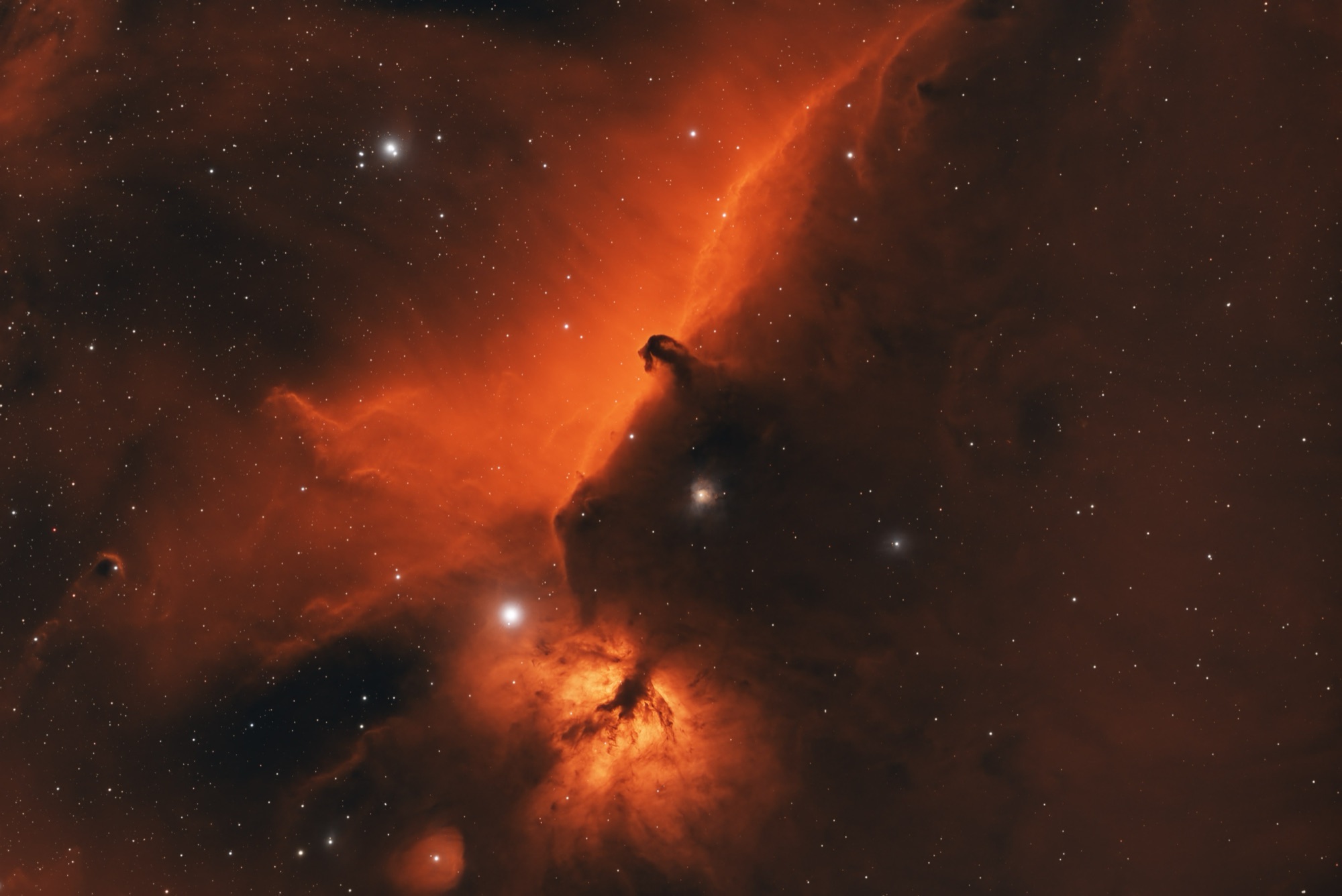 The Horsehead Nebula and the Flame Nebula in Orion, rendered in deep orange and gold, a dark column of dust set against glowing hydrogen.